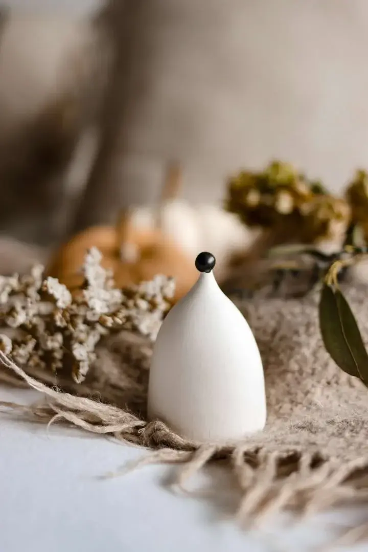 White ceramic figure with black dot by Sara Faulkner