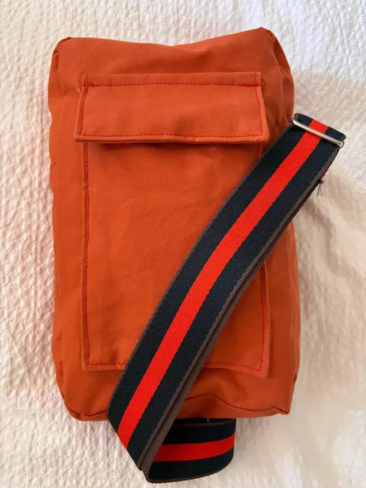 Rust orange canvas crossbody bag with striped strap