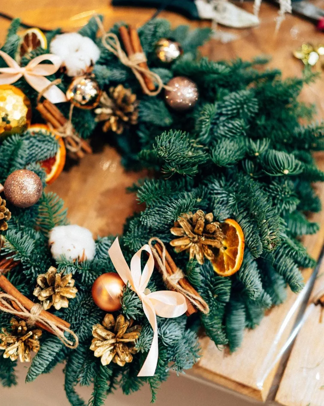 Christmas wreath close up with gold pine cones, cinnamon sticks and dried oranges