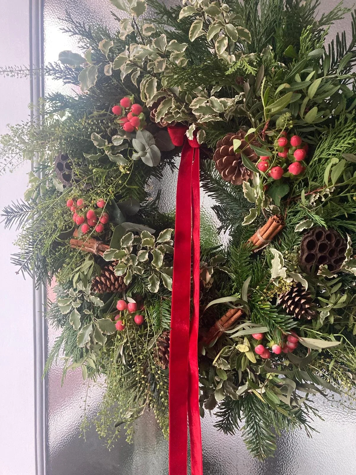 Christmas wreath with red ribbon, berries and pine cones